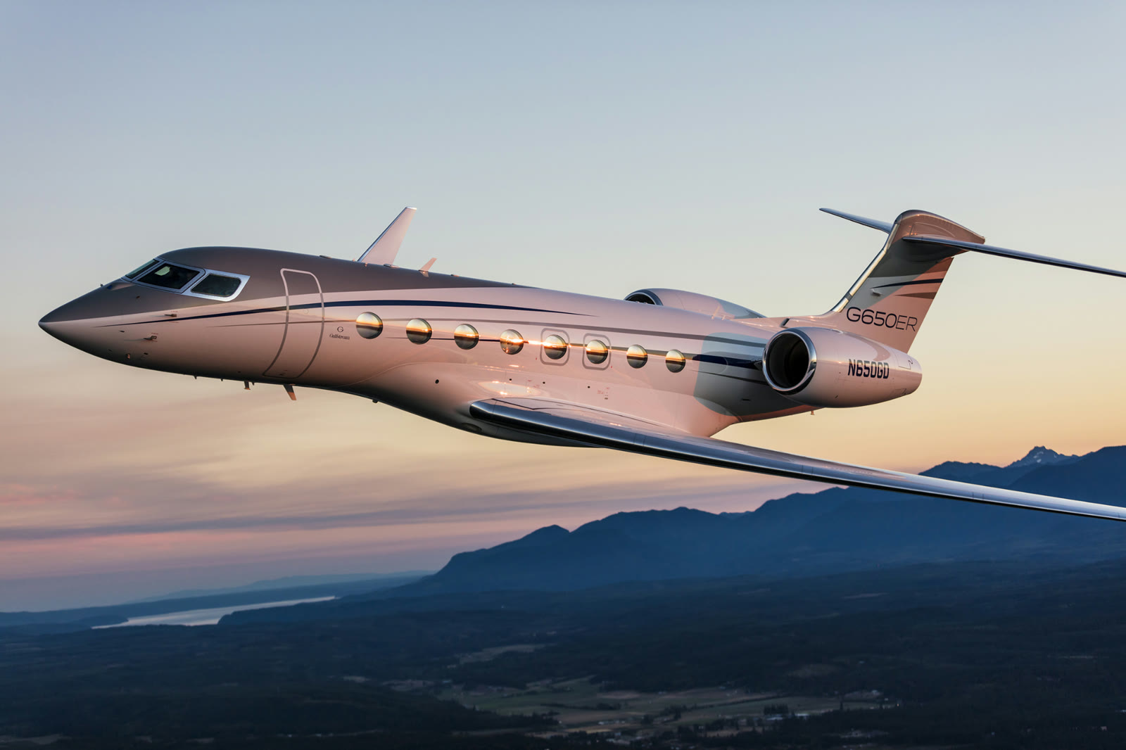 Private jet banking over mountains at dusk